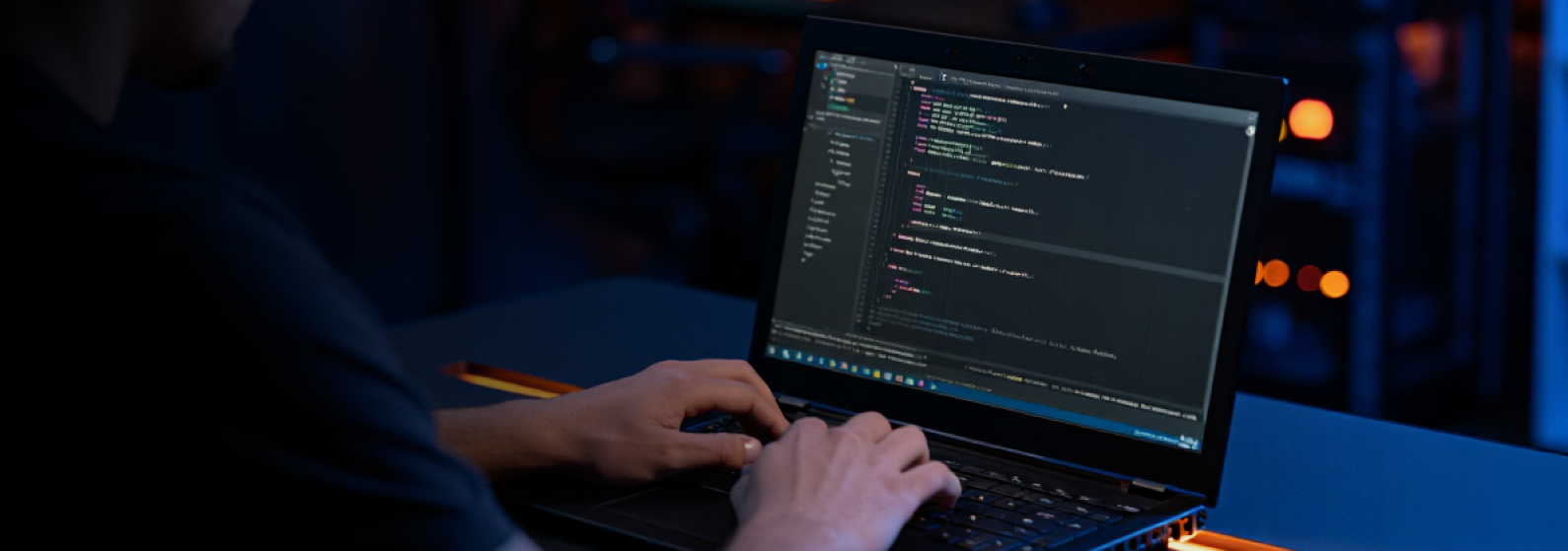 Capa do blog que ilustra o artigo sobre a escolhe de low-code. A imagem mostra uma pessoa branca usando o computador para programar. Vemos apenas suas mãos apoiadas no teclado e a tela do computador com o sistema de programação aberto.